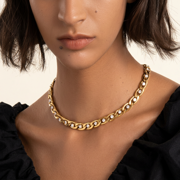 Pretty Bi$h gold chain link crystal choker worn by a brown-skinned model with a black neckline